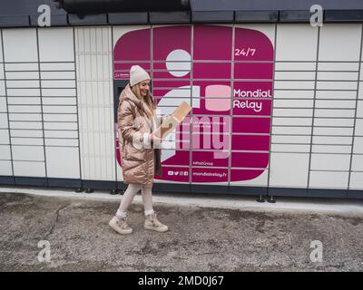 Loriol sur Drome, Francia - 14 gennaio 2023: Raccogliere un pacco da un Mondial `Relay Locker da una giovane donna. Relè Mondial degli armadietti. Scatola di prelievo. Foto Stock