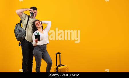 Allegro ragazzo arabo millenario prende fotocamera e donna in occhiali con valigia e biglietti gioire per il viaggio Foto Stock