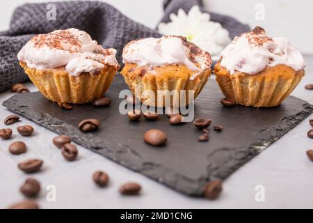 3 cupcakes fatti in casa su una piastrella di pietra nera, fuoco morbido primo piano Foto Stock