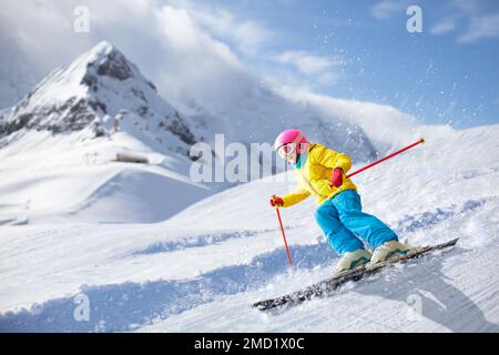 Sci per bambini in montagna. Bambini nella scuola di sci. Sport invernali per bambini. Vacanze di Natale in famiglia nelle Alpi. I bambini imparano a sciare in discesa. Foto Stock