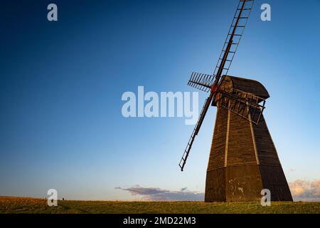 Inquadratura ad angolo basso di un mulino a vento nel mezzo di un campo sotto il cielo azzurro nuvoloso Foto Stock