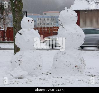 22 gennaio 2023, Sassonia-Anhalt, Wernigerode: Le auto passano dietro due snowmen in piedi in una zona residenziale. In gran parte dei monti Harz ci sono state forti nevicate nella notte alla domenica. Foto: Matthias Bein/dpa Foto Stock