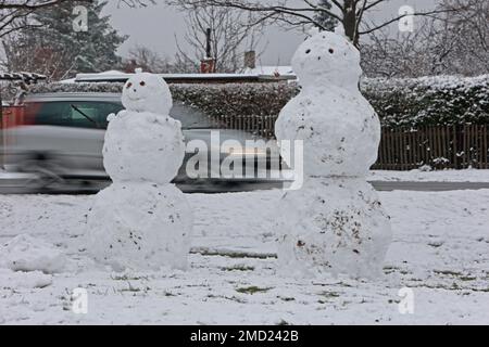 22 gennaio 2023, Sassonia-Anhalt, Wernigerode: Le auto passano dietro due snowmen in piedi in una zona residenziale. In gran parte dei monti Harz ci sono state forti nevicate nella notte alla domenica. Foto: Matthias Bein/dpa Foto Stock