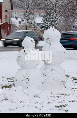 22 gennaio 2023, Sassonia-Anhalt, Wernigerode: Le auto passano dietro due snowmen in piedi in una zona residenziale. In gran parte dei monti Harz ci sono state forti nevicate nella notte alla domenica. Foto: Matthias Bein/dpa Foto Stock