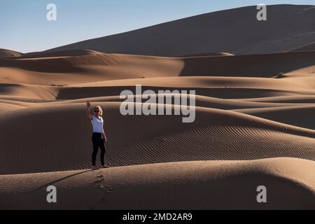 Donna turistica nelle dune di sabbia di Erg Chebbi, deserto del Sahara, Marocco, Nord Africa Foto Stock