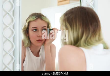 Ragazza adolescente che fa il trucco con eyeliner nero. Foto Stock