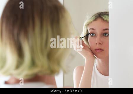 Ragazza adolescente applicare mascara nero su ciglia. Foto Stock