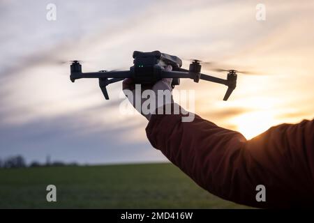 Pilota drone che lancia il drone da Hand al Sunset Foto Stock
