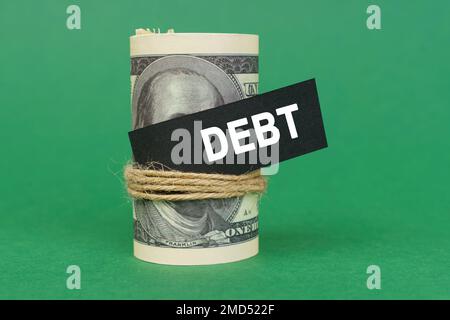 Concetto aziendale. Su una superficie verde, ha rotolato i dollari con un segno nero che dice - debito Foto Stock