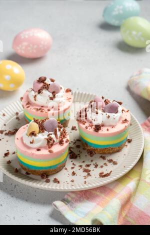 Mini cheesecake di Pasqua con uova caramelle e panna montata. Foto Stock