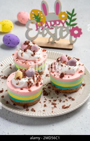 Mini cheesecake di Pasqua con uova caramelle e panna montata. Foto Stock