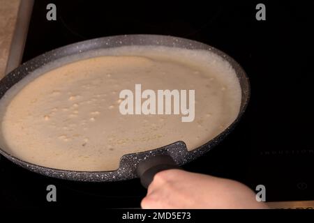 foto preparazione di frittelle sottili in una padella in cucina, sulle mani di stufa nella cornice Foto Stock