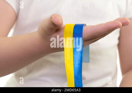 Una ragazza in una T-shirt bianca tiene in mano un nastro giallo-blu (primo piano). Bandiera dello Stato dell'Ucraina. Simbolo nazionale dell'Ucraina. Patriot Foto Stock