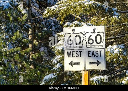 Algonquin Provincial Park, Ontario, Canada - 14 gennaio 2023: Indicazioni stradali per il traffico diretto verso est e ovest lungo l'autostrada provinciale 60 dell'Ontario. Foto Stock