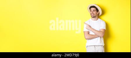 Concetto di turismo e stile di vita. Happy man turista che controlla promo, guardando soddisfatto e puntando il dito sul logo angolo in alto a sinistra, giallo Foto Stock