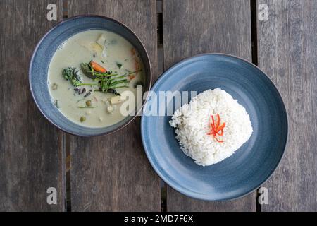 Vista dall'alto verso il basso di un curry vegetariano Verde Tailandese con riso su un tavolo di legno Foto Stock