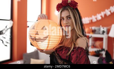 Giovane donna bionda che indossa il costume di katrina tenendo la lampada di zucca in casa Foto Stock