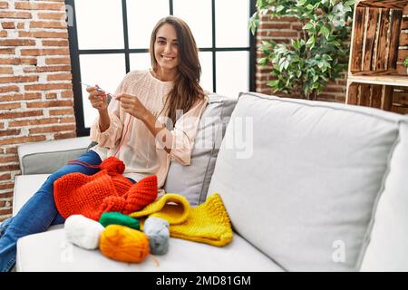 Giovane ispanica sorridente fidata tessendo in finisce a casa Foto Stock