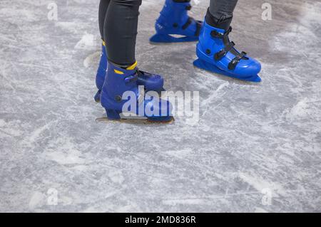 I bambini si divertono a pattinare sul ghiaccio. I pattini di ghiaccio blu sono un dettaglio Foto Stock