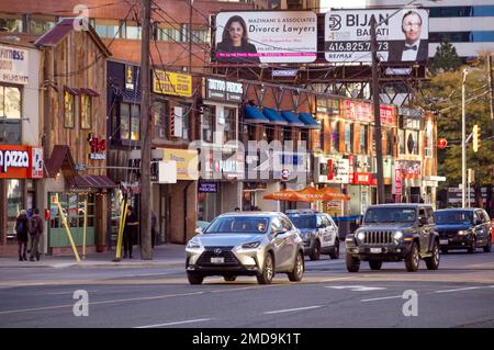 Toronto, Ontario, Canada - 10 03 2022: Calda vista serale autunnale attraverso Younge Street nel quartiere di North York con vecchi edifici a due piani con Foto Stock