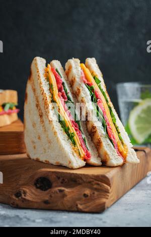 Due panini fatti in casa con salsiccia, formaggio e rucola su un fondo di cemento chiaro Foto Stock