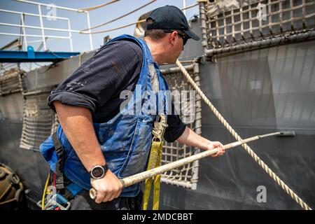 ATTIVITÀ DI SUPPORTO NAVALE BAHRAIN (15 luglio 2022) il compagno di Boatswain Classe 1st Joshua Pelletier dipinge lo scafo della nave da combattimento litoranea USS Sioux City (LCS 11), luglio 15. Sioux City è dislocata nell'area operativa della flotta statunitense 5th per garantire la sicurezza e la stabilità marittima nella regione del Medio Oriente. Foto Stock