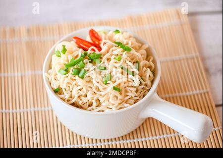 ciotola di tagliatelle con cipollina vegetale e peperoncino su tavolo di legno, pasta istantanea cottura gustoso mangiare con ciotola Foto Stock