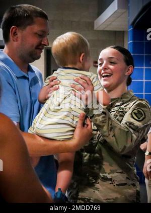 Un soldato della guardia nazionale dell'esercito dell'Iowa assegnato alla 209th Medical Company (Area Support) tiene una persona cara dopo la conclusione di una cerimonia di mandata alla Clear Creek Amana High School di Tiffin, Iowa, il 16 luglio 2022. Alti dirigenti, famiglia e amici si sono riuniti in sala per onorare i 80 soldati che si stanno mobilitando in Polonia a sostegno dell'operazione Atlantic Resolve. Essi forniranno assistenza sanitaria agli ospedali da campo come parte della missione Enhanced Forward Presence della NATO, che consente agli Stati Uniti di fornire deterrenza agli avversari, sostenendo al contempo i nostri partner della NATO. Foto Stock