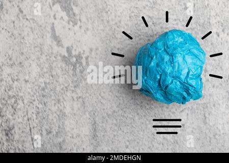 Carta colore blu palla rottami con simbolo lampadina su sfondo grigio. idee di pensiero e concetti di innovazione. Foto Stock