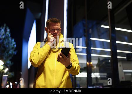 Il turista perplesso guarda lo schermo del suo smartphone per strada. Foto Stock