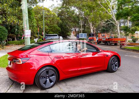 Red Tesla Model 3, modello rilasciato donna e auto, donna guida la sua nuova auto dalla concessionaria Tesla a Sydney, NSW, Australia Foto Stock