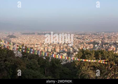 Veduta aerea della capitale nepalese Kathmandu e delle bandiere buddiste di preghiera dal tempio di Swayambhunath. Grande, enorme città asiatica coperta di denso smog con Foto Stock