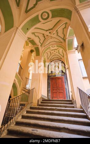 Vista interna di una tipica porta in legno di un appartamento in stucco giallo e verde, sgocciolante scalinata curvilinea a Palazzo dello Spagnolo. Progettato dalla Ba Foto Stock