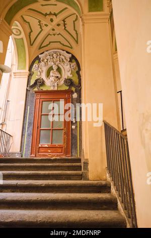 Vista interna di una tipica porta in legno di un appartamento in stucco giallo e verde, sgocciolante scalinata curvilinea a Palazzo dello Spagnolo. Progettato dalla Ba Foto Stock