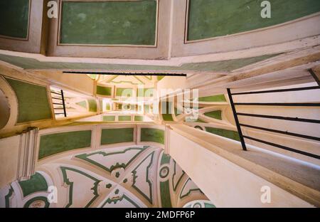 Guardando dritto attraverso lo stucco giallo e verde, sgocciolando una scalinata curvilinea a Palazzo dello Spagnolo. Progettato dall'architetto barocco Ferdi Foto Stock