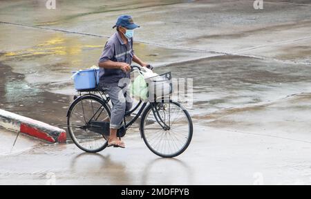 SAMUT PRAKAN, THAILANDIA, 29 2022 SETTEMBRE, Un anziano cavalca una bicicletta sotto la pioggia Foto Stock