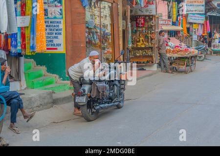 Puttaarthi, India - Gennaio 18,2023: Un uomo indiano che beve il tè ad una motocicletta Royal Enfield Classic a Puttaarthi, negozi di fondo Foto Stock