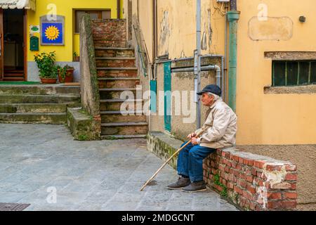 Un vecchio seduto su un muro di pietra, Italia Foto Stock