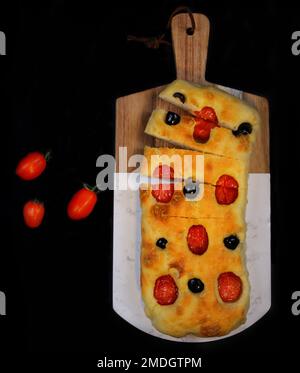 Una vista dall'alto di un focaccia piano forno lievitato pane italiano al forno su un asse di legno da taglio Foto Stock