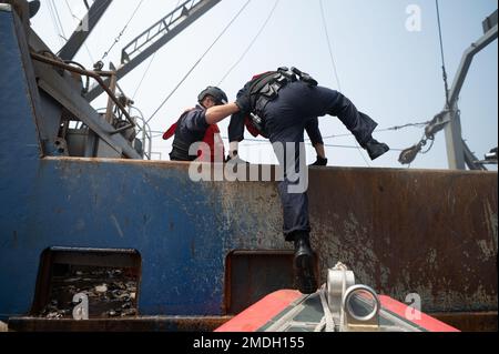 STATI UNITI Guardia costiera Petty Officer 2nd Classe Marcos Collazo, un mater di boatswain a bordo di USCGC Bear (WMEC 901), aiuta Ens. Peyton Bowler, membro della squadra d'imbarco, a bordo di una nave da pesca commerciale prima di iniziare i battelli, Oceano Atlantico, 23 luglio 2022. L'orso e il suo equipaggio si stanno schierando per sostenere l'Organizzazione della pesca nell'Atlantico settentrionale, scoraggiare la pesca illegale e aumentare la consapevolezza del dominio marittimo in collaborazione con le nazioni partner. Foto Stock