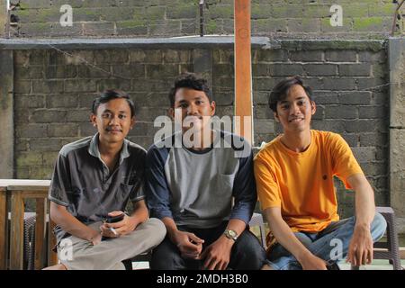 Giacarta, Indonesia 02 24 2020: Uomini che si siedono e sorridono mentre catturano i loro momenti durante le loro vacanze universitarie in una casa nella zona di Giacarta Foto Stock