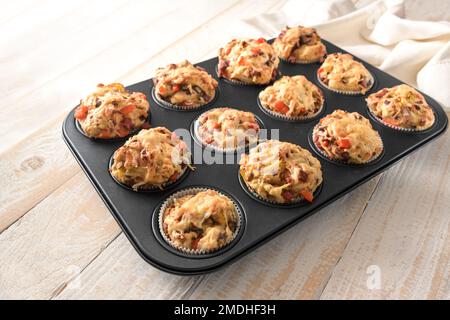 Muffin alla pizza in una teglia da forno appena sfornata, preparati con pasta di lievito con verdure, salsiccia e formaggio, stuzzichini come spuntino per le feste, selezionati Foto Stock