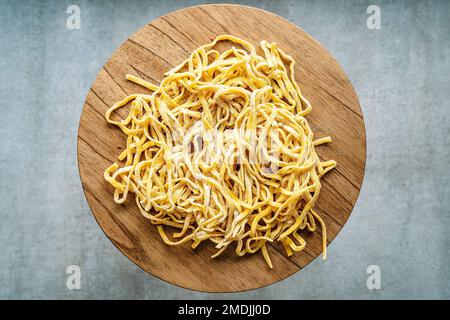 Pasta fatta in casa. Fettuccine fresche crude italiane su un tavolo da cucina in legno. Foto di alta qualità Foto Stock