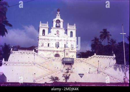 La Chiesa di nostra Signora dell'Immacolata Concezione si trova a Panjim, Goa, India. La chiesa coloniale portoghese in stile barocco è stata costruita nel 1541 come cappella su un lato collina che domina la città di Panjim. La scintillante chiesa bianca è maestosamente famosa per la sua architettura e la sua rampa di scale che zig-zag in cima. Un'altra attrazione della chiesa è la campana agostiniana situata nel campanile, che è anche la seconda campana più grande di Goa. Costruita in stile barocco portoghese, la chiesa si trova su una leggera elevazione, su una collinetta. Foto Stock