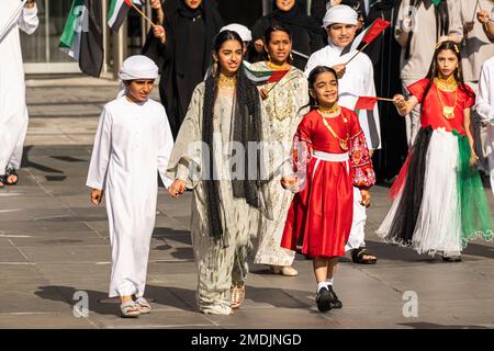 Dubai, Emirati Arabi Uniti - 28 novembre 2022: I bambini in abiti tradizionali sventolano le bandiere degli Emirati Arabi Uniti. Foto Stock