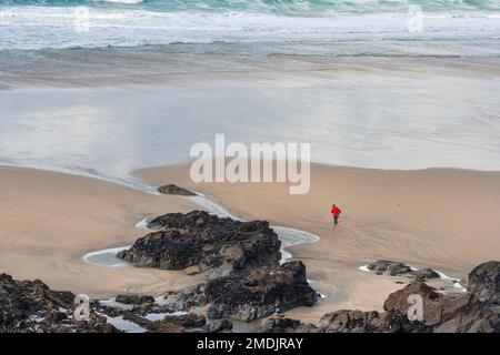 La piccola figura di persona che corre lungo la costa su una ventosa Fistral Beach a Newquay in Cornovaglia. Foto Stock