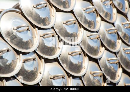 un sacco di coperchi pentola come sfondo alla luce del sole, un coperchio pentola, utensili da cucina Foto Stock