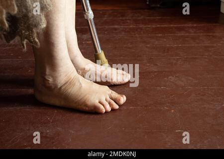 piedi di una vecchia nonna su un pavimento di legno sporco, solitudine, piedi di un vecchio uomo, un pensionato in povertà Foto Stock