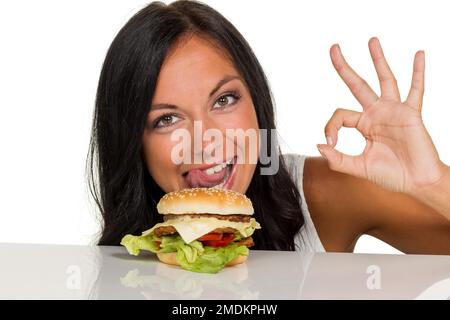Giovane donna con hamburger che fanno segno OK Foto Stock
