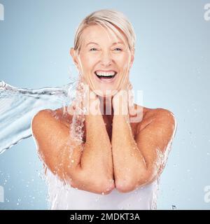 Ritratto, donna anziana e spruzzi d'acqua per dermatologia, cosmetici e cura della pelle su sfondo grigio studio. Faccia, donna matura o donna anziana bagnata Foto Stock